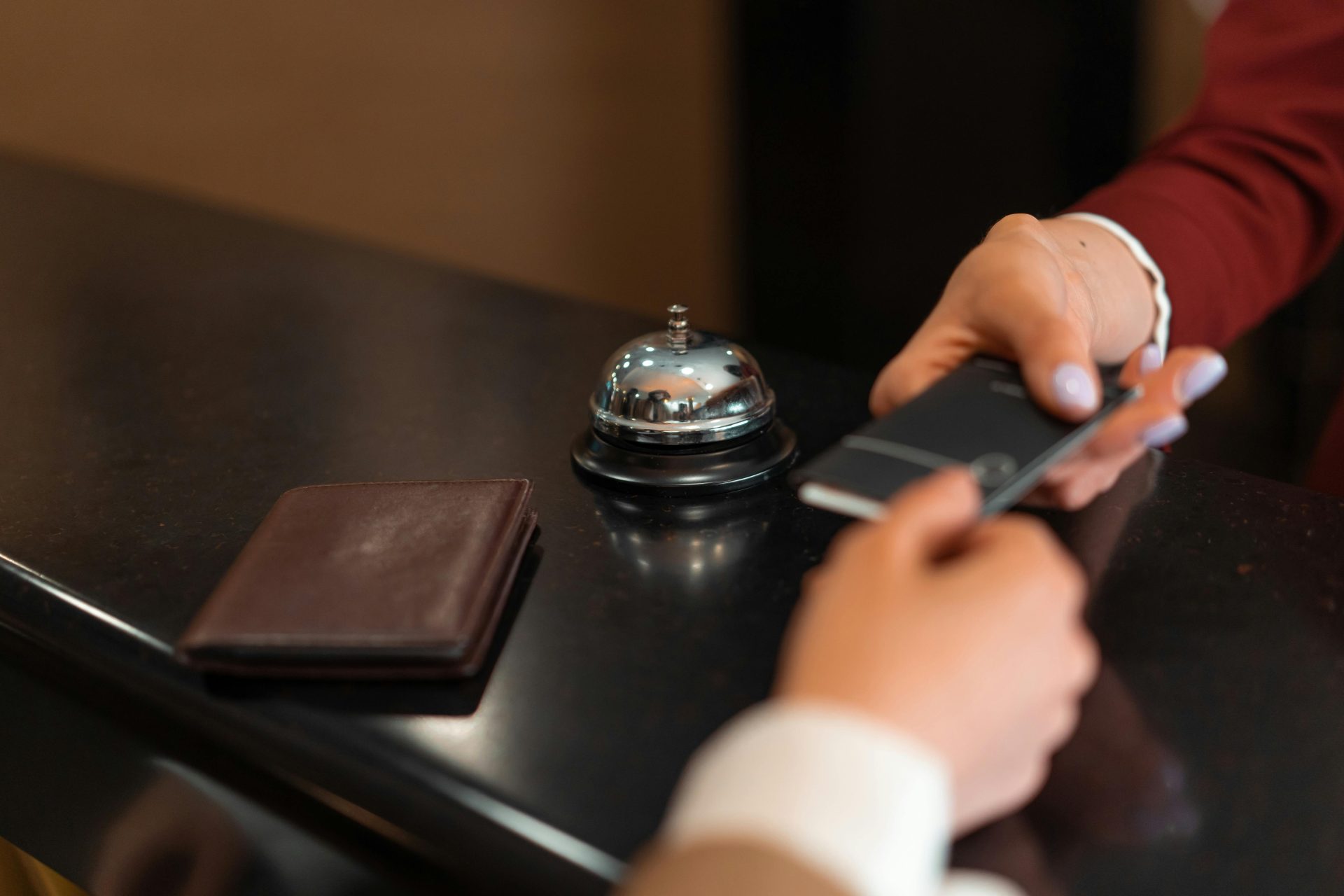 Gros plan sur une procédure d'enregistrement à l'hôtel, avec paiement par smartphone et carte bancaire à la réception.